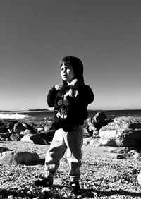 Full length of boy standing on beach against clear sky