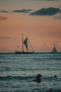 Silhouette sailboat sailing on sea against sky during sunset