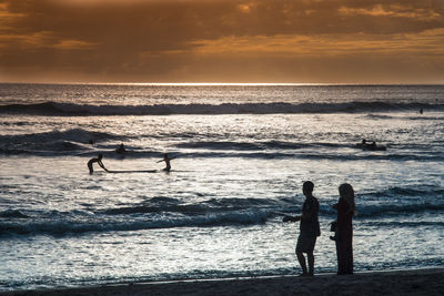 Silhouette of people at beach during sunset