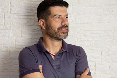 Portrait of young man looking away against wall