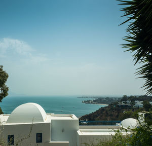 Buildings by sea against sky