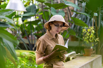 Woman holding umbrella while standing by plants