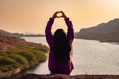 Isolated young girl at mountain top with lake view backbit shot from flat angle