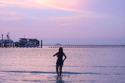 Silhouette woman standing on beach against sky during sunset