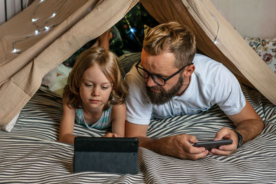 Father and son playing in a teepee tent at home.