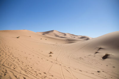 Scenic view of desert against clear blue sky