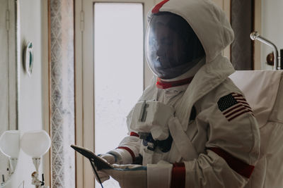 Man using phone while wearing spacesuit at home