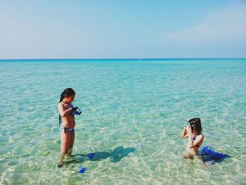 Sisters in sea against sky