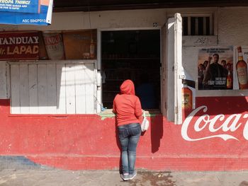 Full length of woman standing by red wall