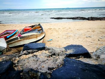 Boat moored on beach against sky