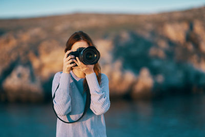 Portrait of man photographing against sea