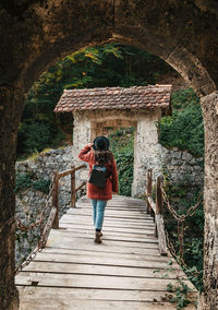 Rear view of woman on wooden footbridge, old castle, medieval.