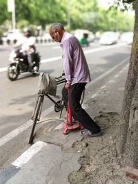 Side view of man pumping bicycle on road in city