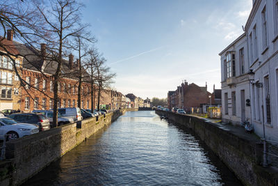 Canal amidst buildings in city against sky