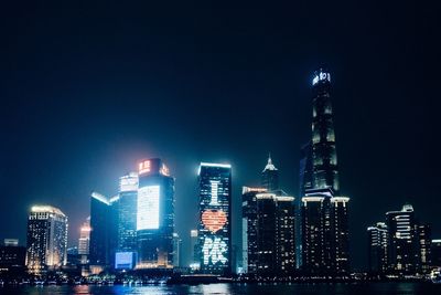 Illuminated buildings in city against sky at night