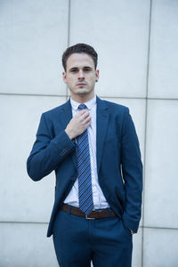 Portrait of young man standing against wall