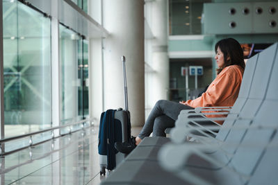 Seated woman, looks through the airport window, waiting for her flight.