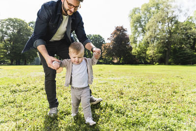 Father helping son to walk in a park