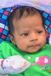 Close-up of cute baby boy lying on bed at home