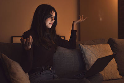 Young woman sitting on sofa at home