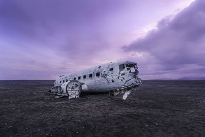 Abandoned airplane at beach against sky