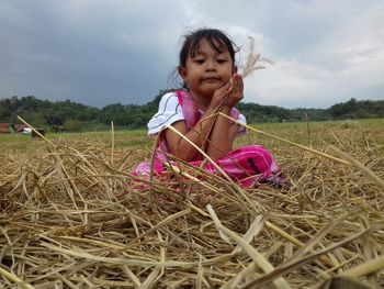 Cute girl standing on field against sky