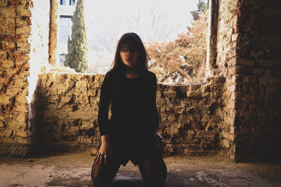 Full length of woman standing against wall