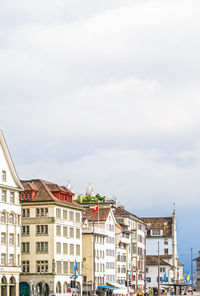 Buildings in town against cloudy sky