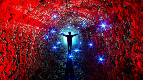 Rear view of man standing on illuminated cross at night