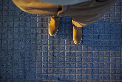 Low section of man standing on footpath during sunset