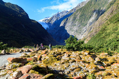 Rear view of people standing on rock against sky