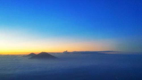 Scenic view of silhouette mountains against clear sky during sunset