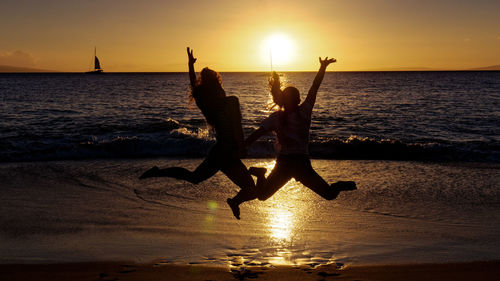 Silhouette people at beach during sunset