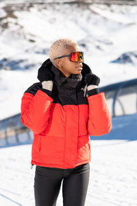 A african american woman wearing goggles standing in snowy mountain during winter	