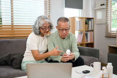 Female friends using phone while sitting at home