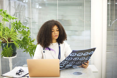 Portrait of young woman using laptop while sitting on table