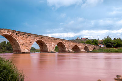 Arch bridge over river against sky