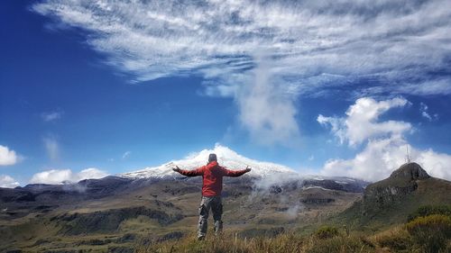 Rear view of person standing on mountain against sky