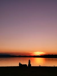 Silhouette people on beach against sky during sunset