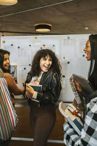 Happy woman shouting while looking at friends checking grades in college