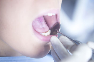 Cropped hand of dentist examining mouth