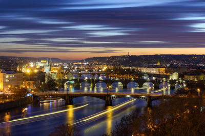 Illuminated bridge over river in city at night