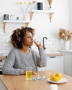 Portrait of smiling young woman using mobile phone while sitting on table