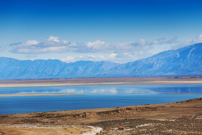 Scenic view of lake and mountains against blue sky