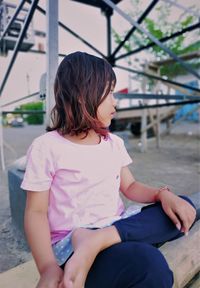 Rear view of girl sitting outdoors