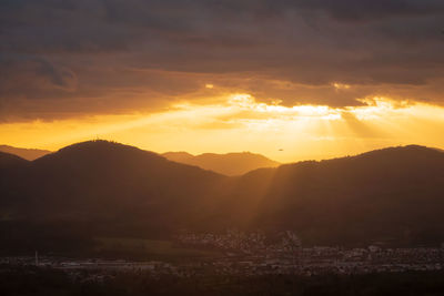 The golden rays of the setting sun shine over a mountain ridge in the murgtal in the black forest