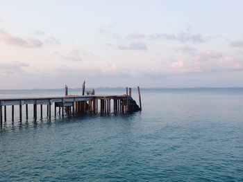 Pier on sea against sky during sunset