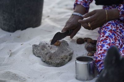 Midsection of woman holding hands on sand at beach