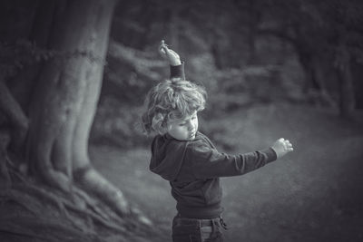 Full length of boy standing by tree