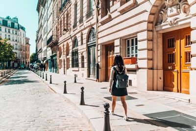 Woman walking on sidewalk by buildings